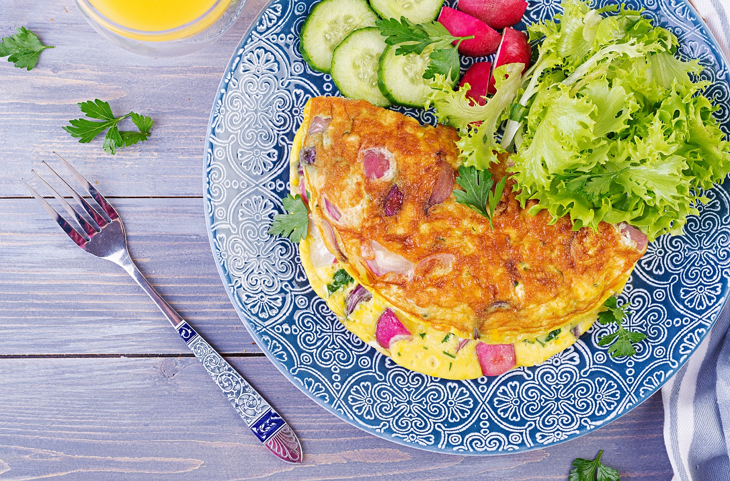 Breakfast. Omelette with radish, red onion and fresh salad on blue plate. Frittata - italian omelet. Top view